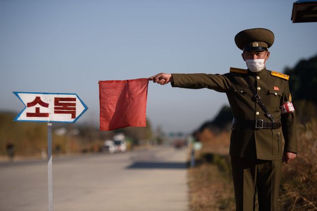 in this photo taken on october 29, 2020, a public security officer uses a red flag to stop a taxi for disinfection as part of preventative measures against the covid 19 coronavirus, on a road at the entrance to wonsan, kangwon province photo by kim won jin  afp photo by kim won jinafp via getty images