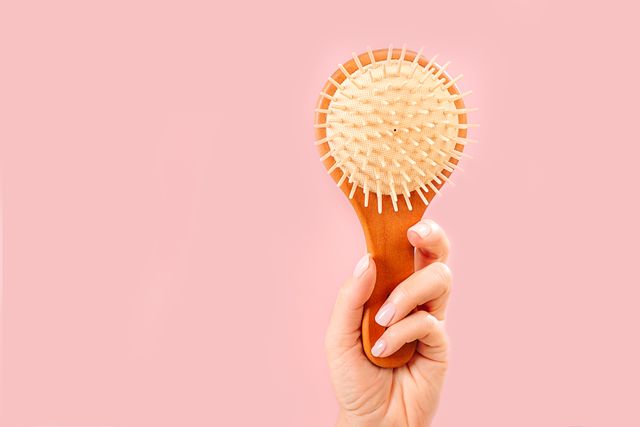 woman hands holding natural bamboo wooden comb brush on pastel pink background  routine step for healthy skin and hair care trendy pink nude manicure  beauty and cosmetic concept copy space close up