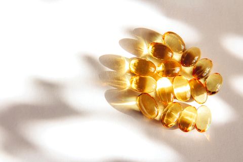 shiny yellow fish oil capsules on a light background with shadows of focus on the table vitamin e copy space for your text