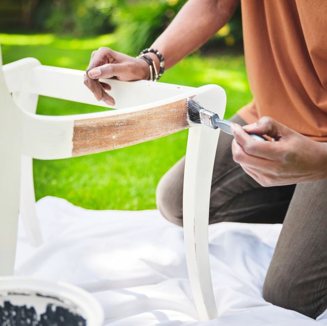 an unrecognizable senior man painting a wooden chair in the garden closeup of a mature man fixing an old chair in the backyard