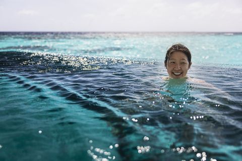smiling mid adult woman swimming in infinity pool