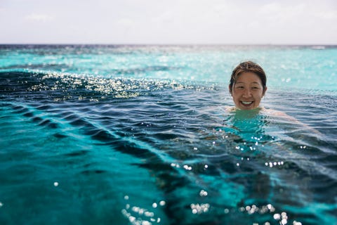 smiling mid adult woman swimming in infinity pool