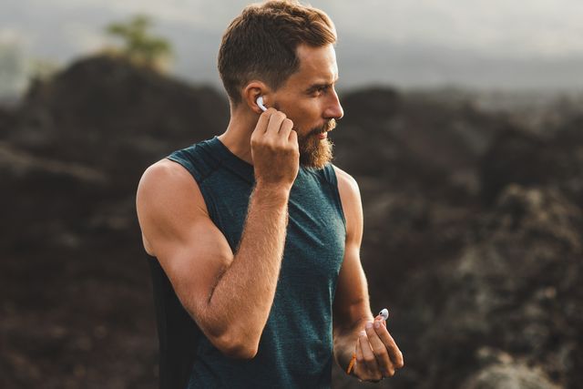 man using wireless earphones air pods on running outdoors active lifestyle concept