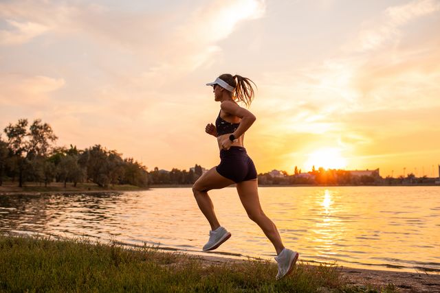 woman trail running by the nature with beautiful lakeside sunset view jogging outdoors in evening mental health, active lifestyle sports background and room for copy space