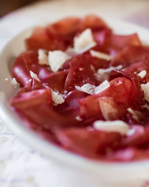 a plate of bresaola with parmesan cheese, olive oil and pepper