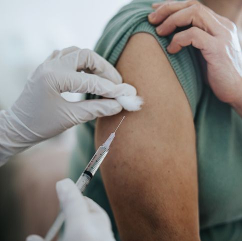 close up of senior asian woman getting covid 19 vaccine in arm for coronavirus immunization by a doctor at hospital elderly healthcare and illness prevention concept