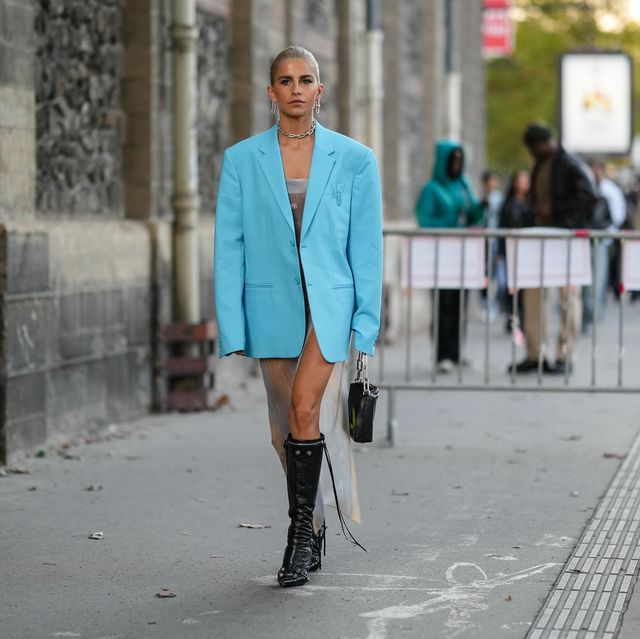 paris, france   september 29 caroline daur wears gold large earrings, a matching silver large chain necklace, a blue oversized blazer jacket, a white ribbed wool asymmetric long dress, a black shiny leather handbag from off white, black shiny leather nailed  studded pointed knees boots from balenciaga , outside off white, during paris fashion week   womenswear springsummer 2023, on september 29, 2022 in paris, france photo by edward berthelotgetty images