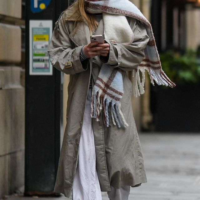 paris, france   november 10 a passerby wears a pale blue  beige  brown checkered print pattern wool  fringed large scarf, a beige and black striped print pattern t shirt, a pale khaki long coat, white wide legs pants , during a street style fashion photo session, on november 10, 2022 in paris, france photo by edward berthelotgetty images