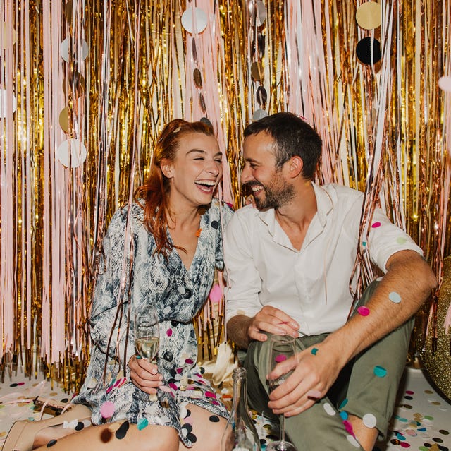 new years decoration ideas laughing couple in front of photo backdrop on new year's eve