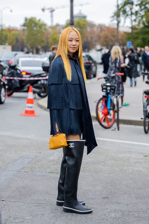 paris, france october 03 niki wu jie wears orange bag, black rain chanel boots, navy fringed jacket outside zimmermann during paris fashion week womenswear springsummer 2023 day eight on october 03, 2022 in paris, france photo by christian vieriggetty images