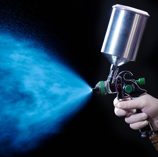 a gloved hand shooting blue paint out of a handheld paint sprayer