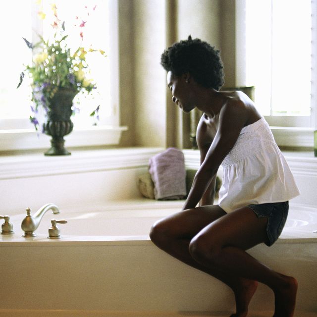 Young woman sitting on edge of bathtub