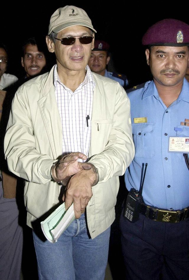 kathmandu, nepal  convicted criminal charles sobhraj l is led away in handcuffs by a nepalese police officer from kathmandu district court, 20 october 2003, following a court hearing  the court has ordered the police to detain the french national, sobhraj, 59, pending further investigation into his involvement in a 1975 double murder case afp photodevendra m singh  photo credit should read devendra m singhafp via getty images