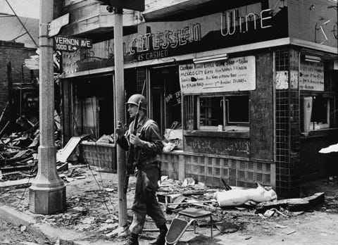an armed national guard patrolman leans against a street sign, smoking a cigarette and standing in rubble following the watts riots, los angeles, california, august 1965 photo by hulton archivegetty images