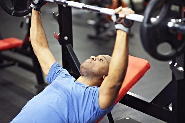 healthy black male preparing to perform a barbell bench press in gym
