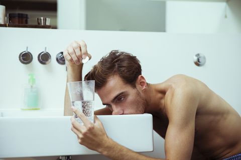 Hungover man watching effervescent tablets in bathroom