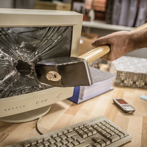 businessman hitting hammer on computer monitor in office businessman hitting hammer on computer monitor in office