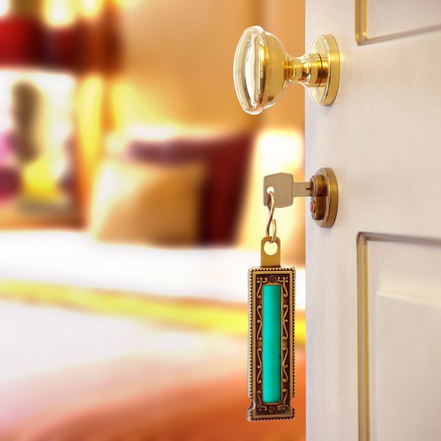 hotel room or apartment doorway with key and keyring key fob in open door and bedroom in background