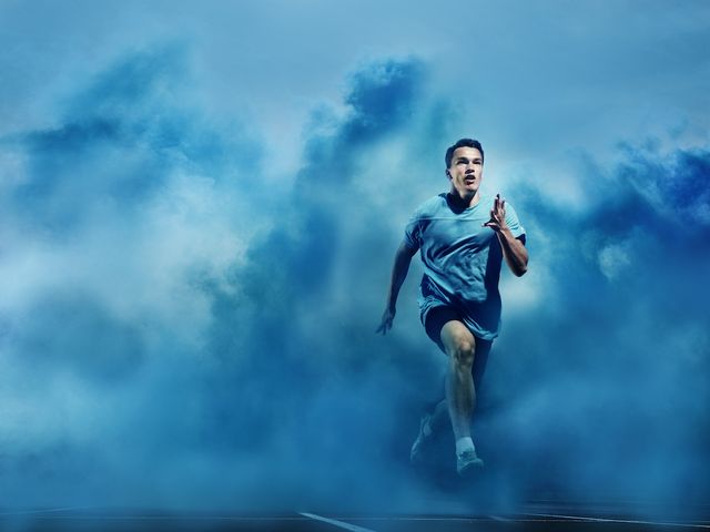 male athlete running through blue smoke