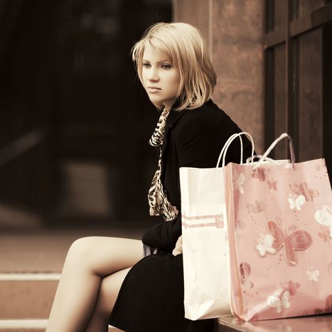 sad young woman with shopping bags at the mall window