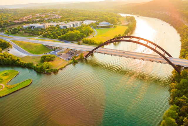panoramic aerial view from helicopter of 360 bridge on colorado river near austin texas, looking west at sunset