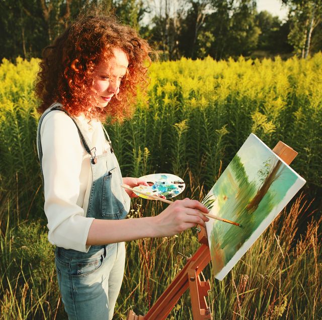 young woman painting landscape in the open air