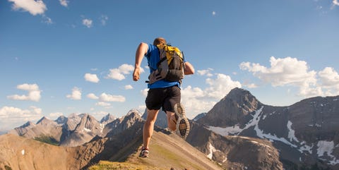 Trail runner in mid air stride, on mountain ridge