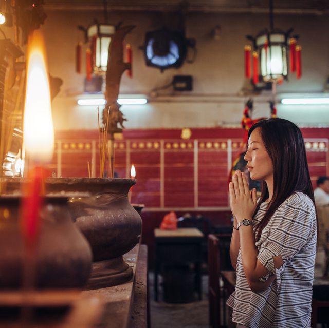 young asian female put her palms together praying sincerely and devoutly in a temple