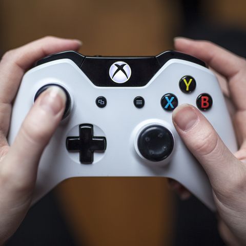 gothenburg, sweden   january 17, 2015 a close up shot from above of a young womans hands holding a white xbox one controller as she is playing a video game natural lighting, shot on wooden background with shallow depth of field