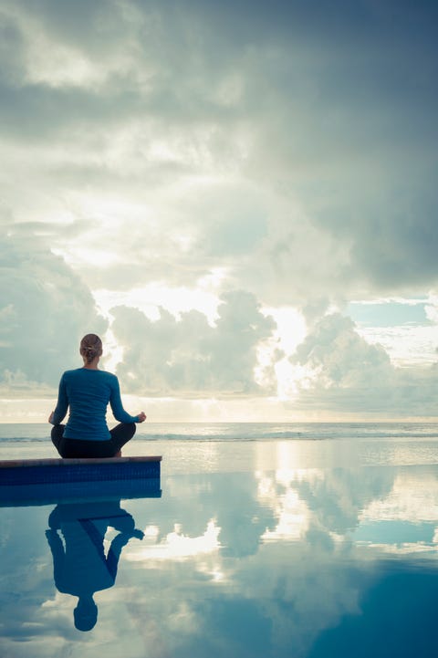 Caucasian woman meditating near swimming pool meditations
