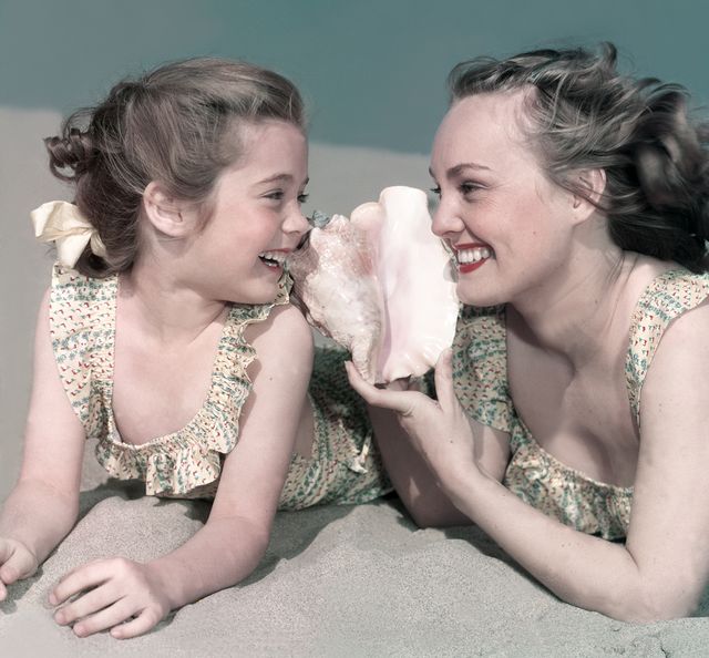 madre e hija con una concha en la playa los angeles, california, años 50