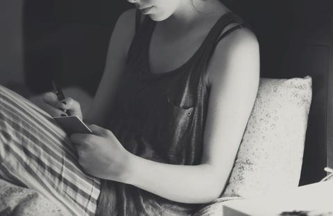 Young woman writing diary in bed Young woman writing diary in bed