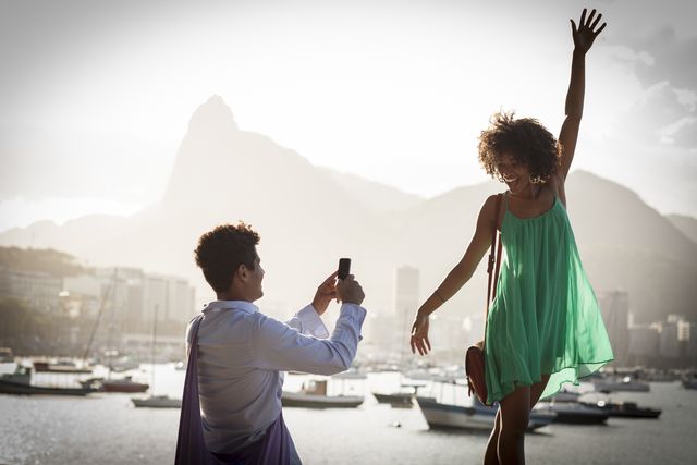 young brazilian couple in love, taking photos with christ the redeemer in the background, tourists on vacation, happy and smiling at dusk