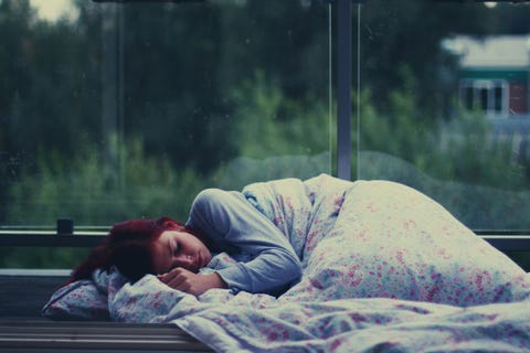 Young woman sleeping at bus shelter