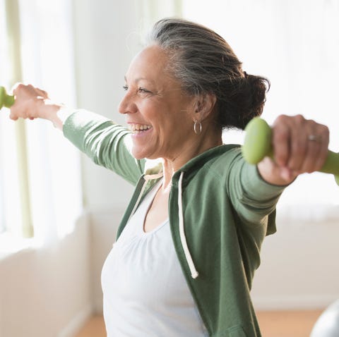 Older Hispanic woman lifting weights in living room Older Hispanic woman lifting weights in living room