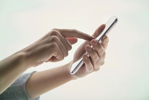 Mano de mujer joven con un dispositivo de información portátil sobre un fondo blanco.