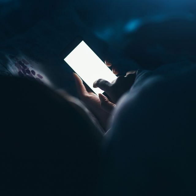woman scrolling on her phone in the dark