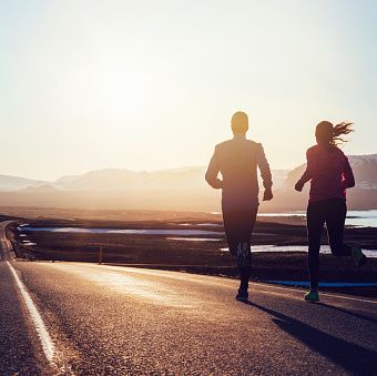 un hombre y una mujer corren juntos sobre el asfalto para ilustrar un reportaje sobre cómo cuidar tus pies