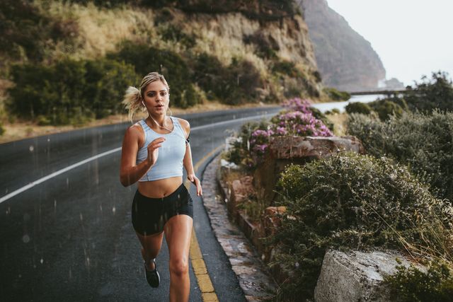 fitness woman running on highway around the mountains female athlete training outdoors during rain
