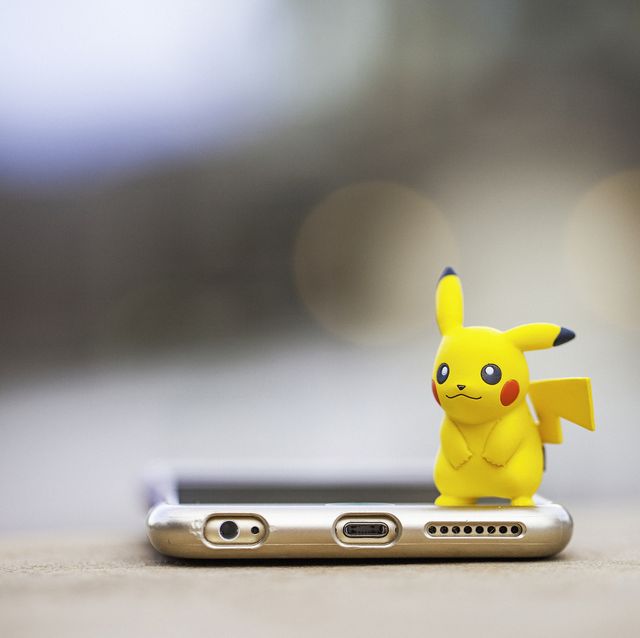 peyton, colorado, usa   august 17, 2016 a horizontal shot of the pokemon go character pikachu, standing on top of an apple iphone 6 plus the character and phone are on a wall outdoors, in front of a defocused street scene in peyton, colorado the figurine is made by tomy