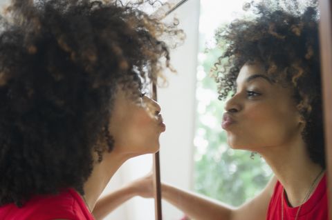 Mixed race woman puckering in mirror