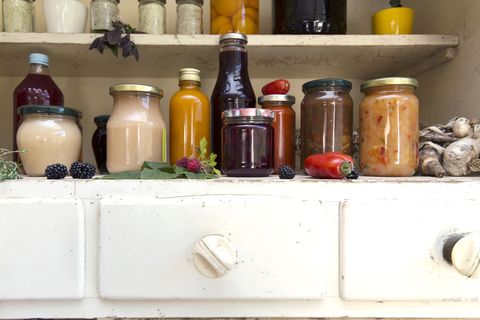 Jars and bottles of home-made food on retro style kitchen cabinet