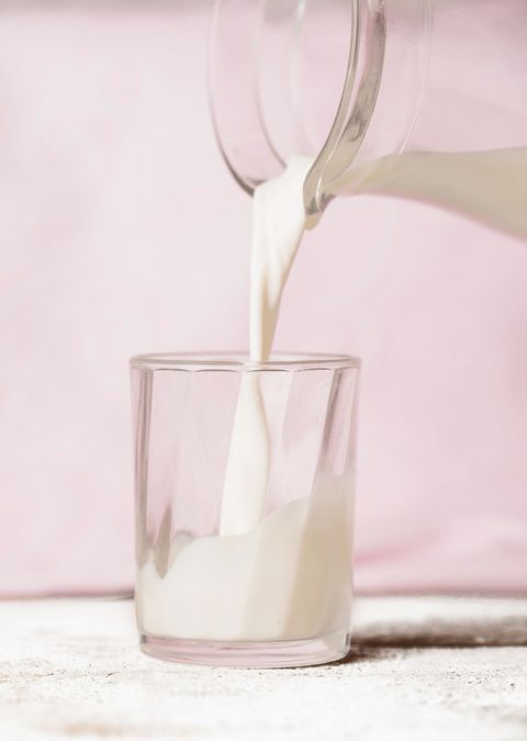 Pouring milk into glass, pink background
