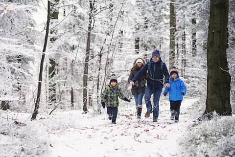 Father with kids running in beautiful winter forest