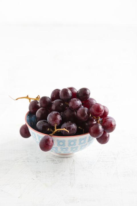 Bowl of red grapes on white ground