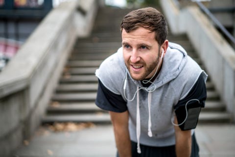 young man running outdoors listening to music with headphones   sports training concepts