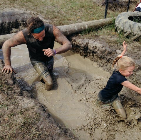 Father and daughter enjoying a mud run father and daughter going through obstacle during a mud run