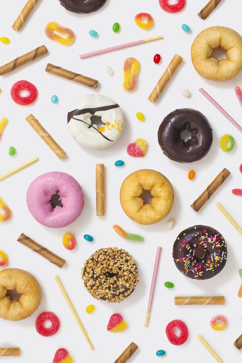 Colourful glazed donuts, candy and snacks on white background.