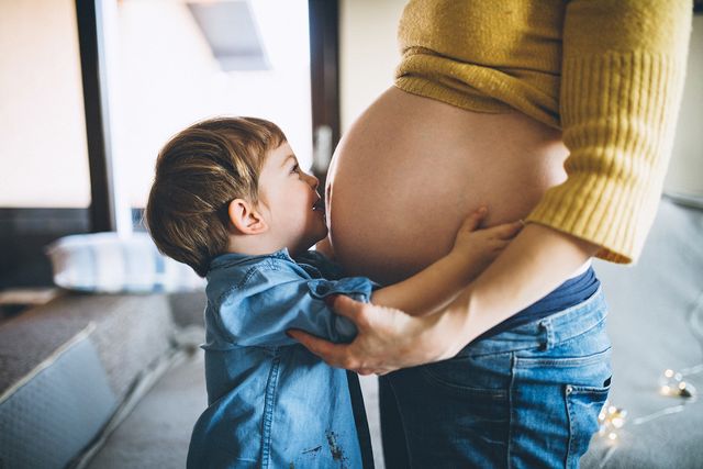 mujer embarazada con un bebé besándole la barriga
