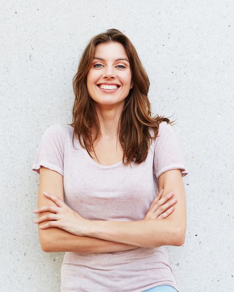 attractive young woman smiling against white wall
